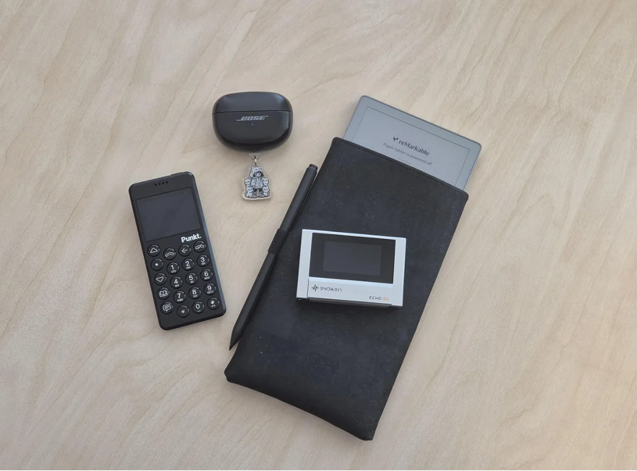 Everyday carry layout shared to r/dumbphones — Kindle with Oscar Wilde sketch, iPod, notebook, keys, Casio watch, glasses.