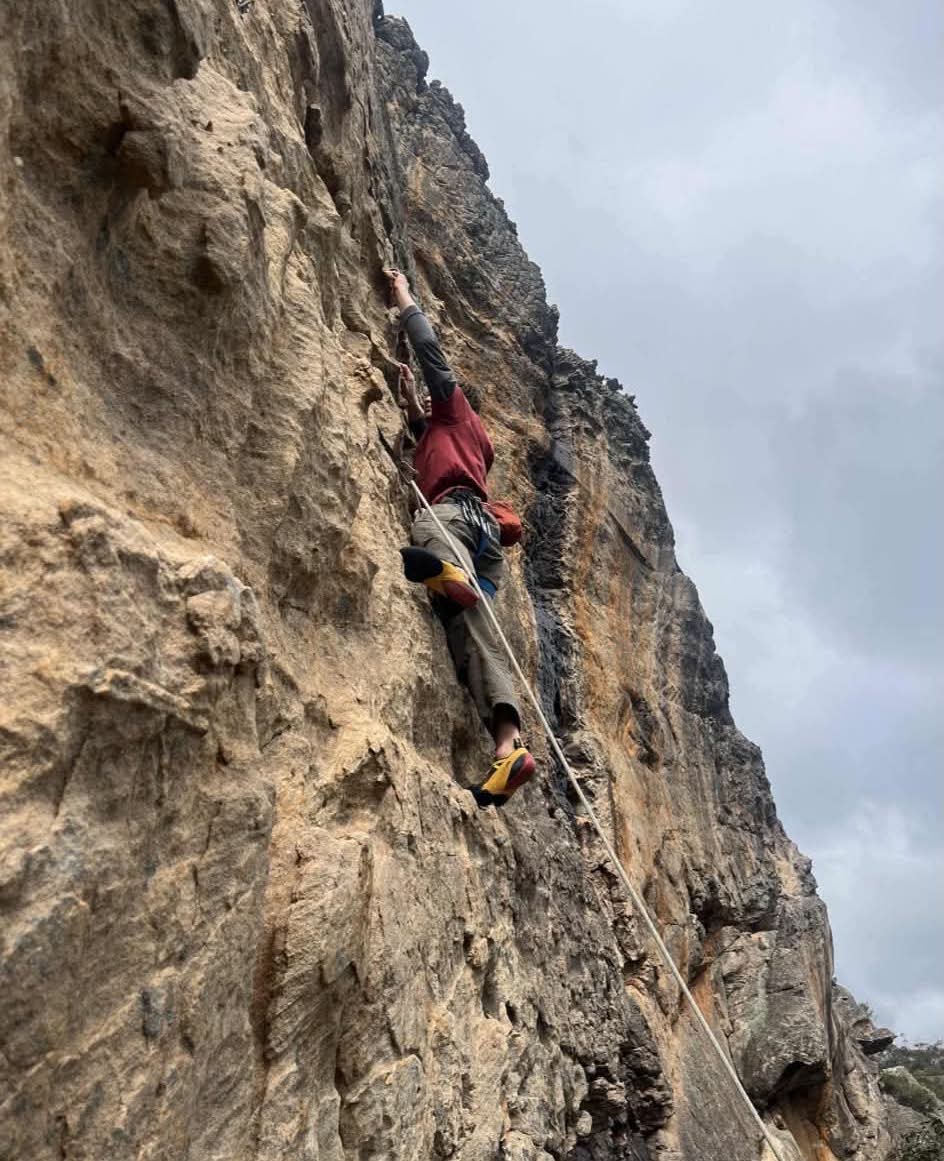A climber ascending a rock face at an outdoor crag.