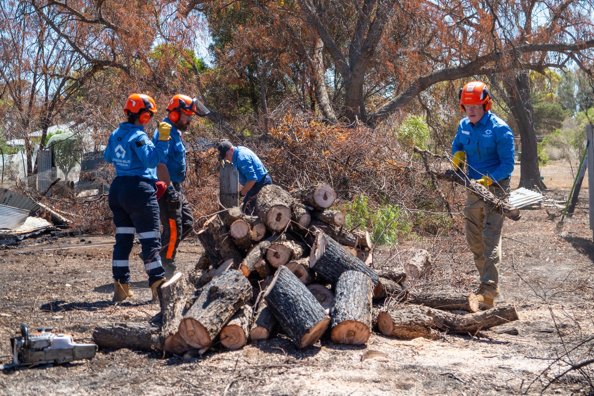 DRA crew stacking cleared timber into a log pile.